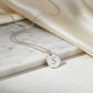 Silver necklace with a round pendant featuring the letter 'S' on a marble background