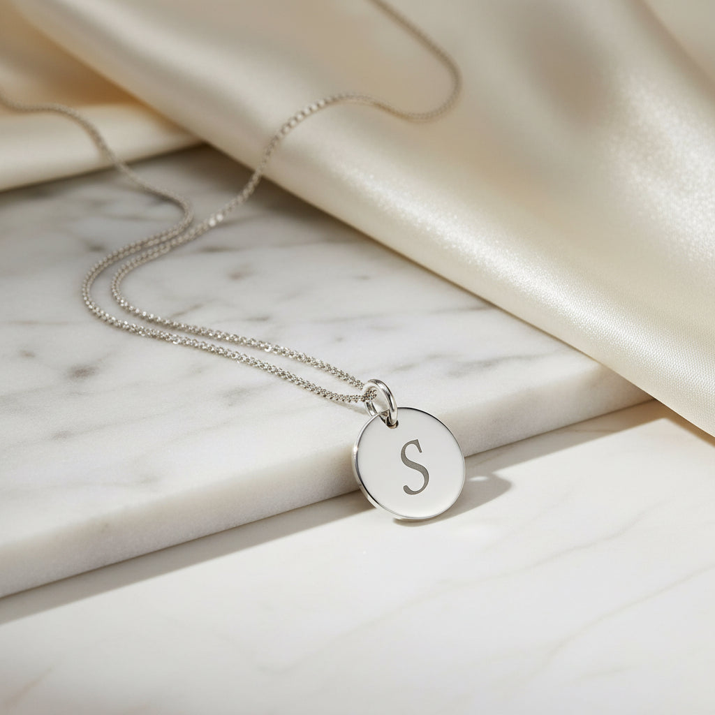 Silver necklace with a round pendant featuring the letter 'S' on a marble background