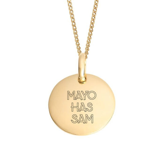 A gold round pendant necklace engraved with the text 'MAYO HAS SAM' in a thin outlined font, suspended from a gold chain against a plain white background.
