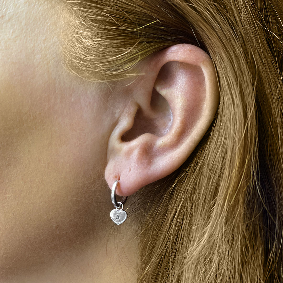 Silver hoop earrings with heart charm shown on model