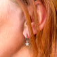 Silver huggie earrings with a star charm shown on a model